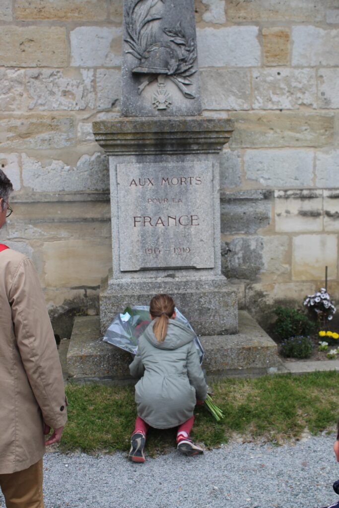 Jeune fille déposant un bouquet de fleur sur le monument aux morts lors de la commémoration du 8 mai